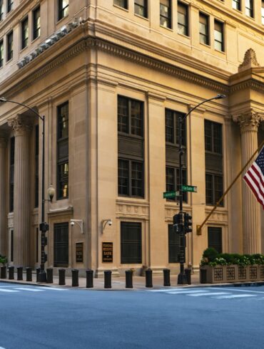 a large building with columns and a flag on the corner