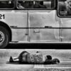 grayscale photography of person laying on ground near bus