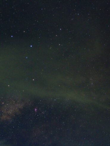 astrophotography red and white tower with satellites under milky way