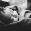 a black and white photo of a baby wrapped in a blanket