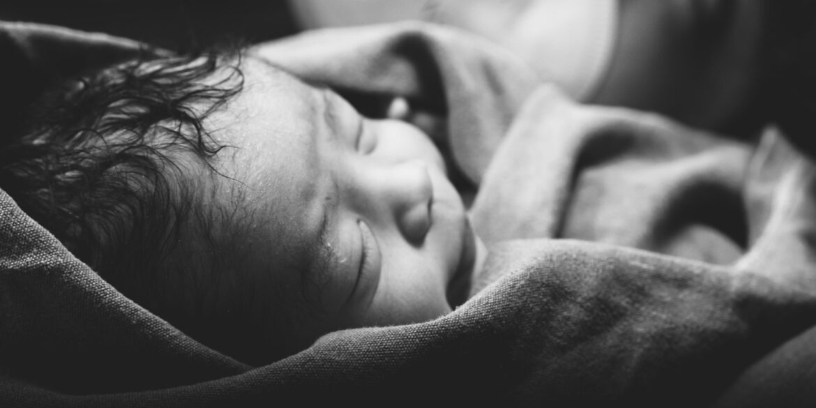 a black and white photo of a baby wrapped in a blanket