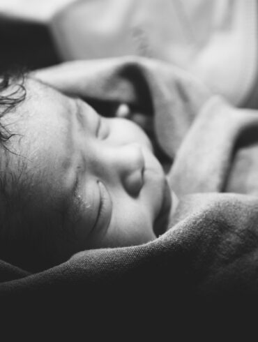 a black and white photo of a baby wrapped in a blanket