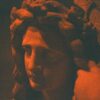 A statue's face glows in an orange hue.