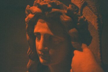 A statue's face glows in an orange hue.