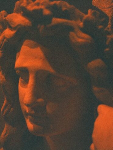 A statue's face glows in an orange hue.