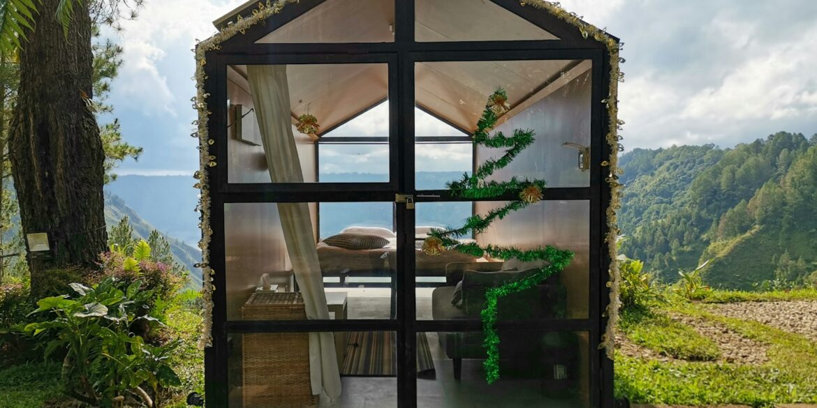 a small house made out of glass with a view of the ocean