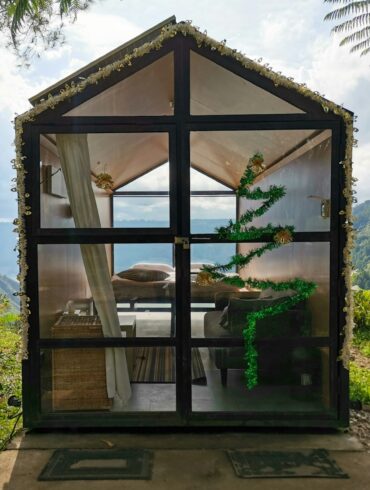 a small house made out of glass with a view of the ocean