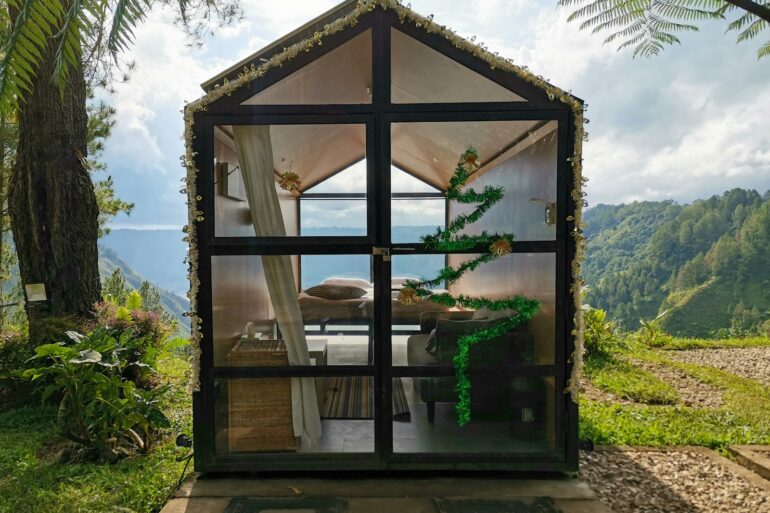 a small house made out of glass with a view of the ocean