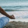 person in blue shorts sitting on beach shore during daytime