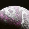 A purple and white marbled object on a black background