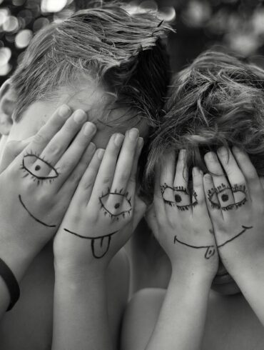 woman in black tank top covering face with hands