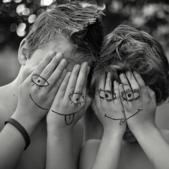 woman in black tank top covering face with hands