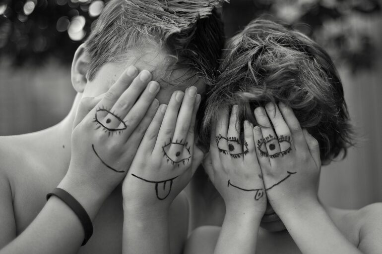 woman in black tank top covering face with hands