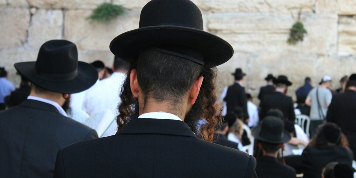 a man in a black suit and hat standing in front of a crowd of people