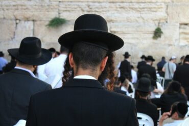 a man in a black suit and hat standing in front of a crowd of people