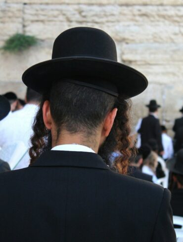 a man in a black suit and hat standing in front of a crowd of people