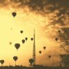 silhouette hot air balloons under cloudy skies during golden hour