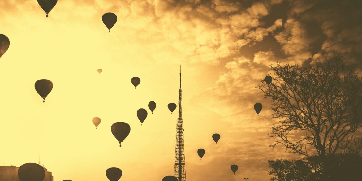 silhouette hot air balloons under cloudy skies during golden hour
