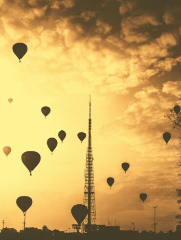 silhouette hot air balloons under cloudy skies during golden hour