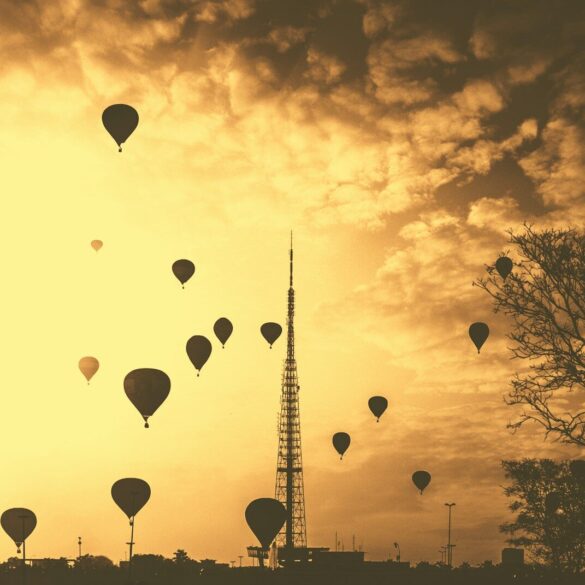 silhouette hot air balloons under cloudy skies during golden hour