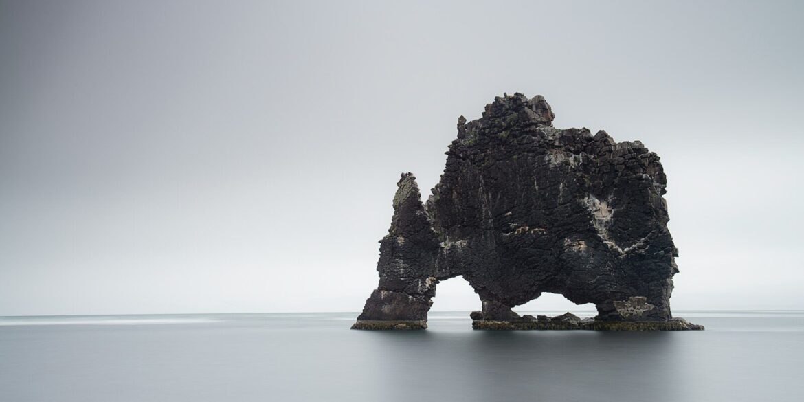 black rock formation on body of water