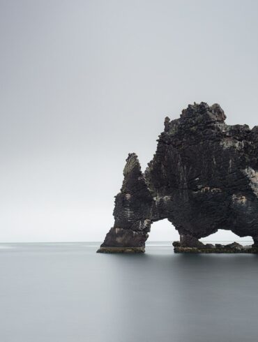 black rock formation on body of water