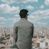 a man sitting on a ledge looking over a city