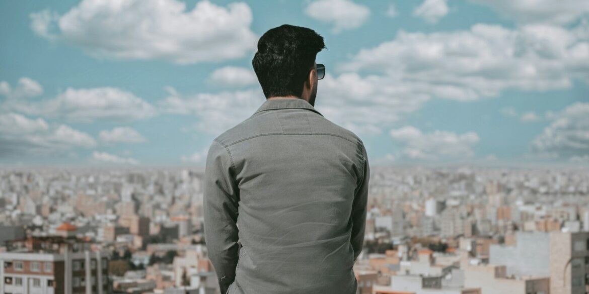 a man sitting on a ledge looking over a city