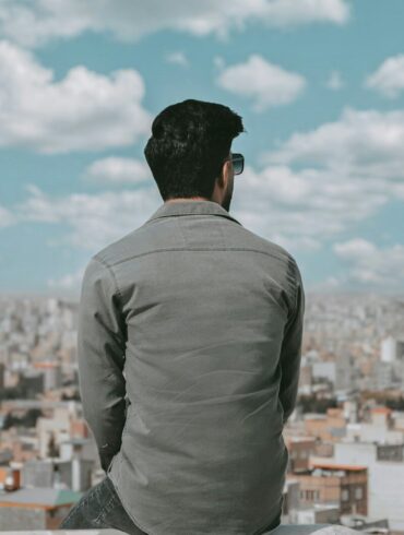 a man sitting on a ledge looking over a city