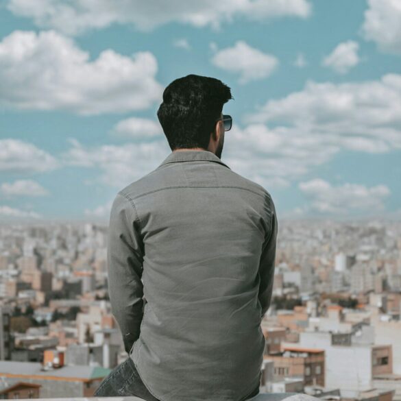 a man sitting on a ledge looking over a city