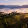 White church on a hilltop overlooking misty valley at sunrise