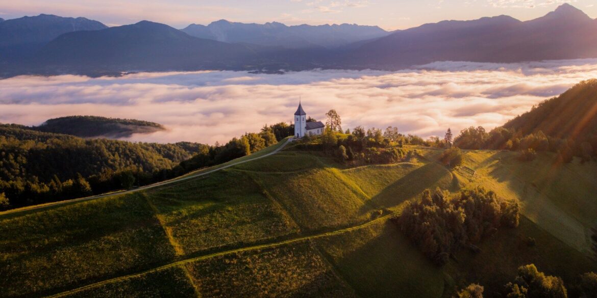 White church on a hilltop overlooking misty valley at sunrise