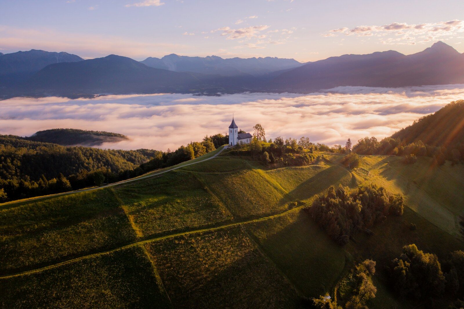 White church on a hilltop overlooking misty valley at sunrise