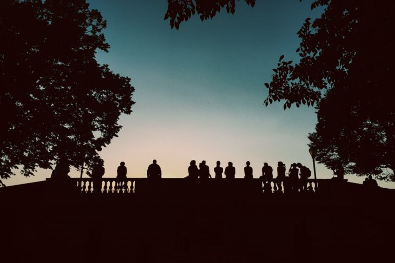 silhouette of people standing beside bridge during blue hour