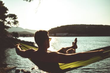 silhouette of woman sitting on hammock by the sea during daytime