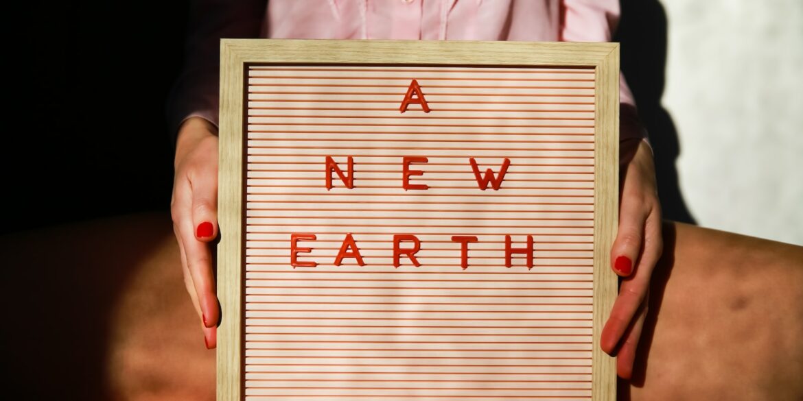 a woman holding a sign that says a new earth