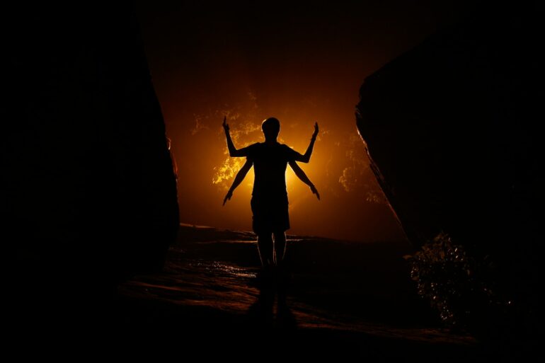 a person standing in the dark with their arms outstretched
