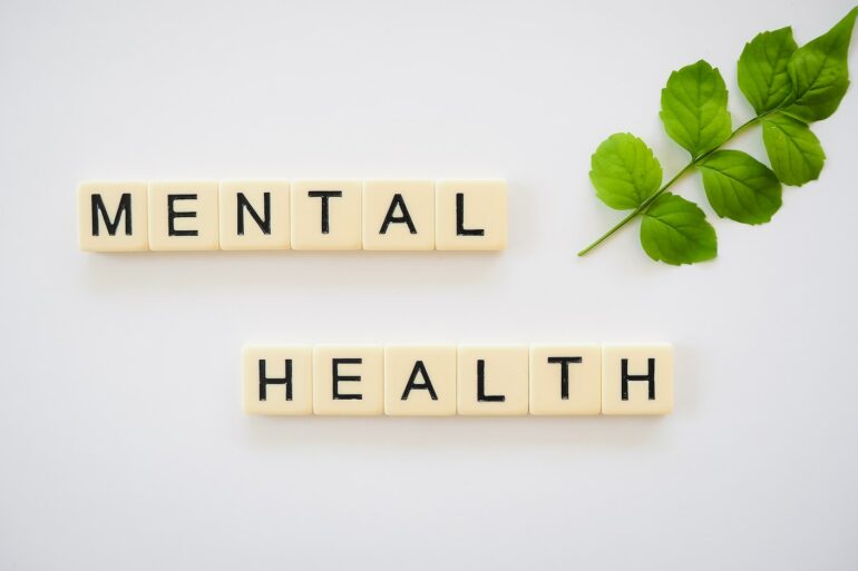 the word mental health spelled with scrabbles next to a green leaf