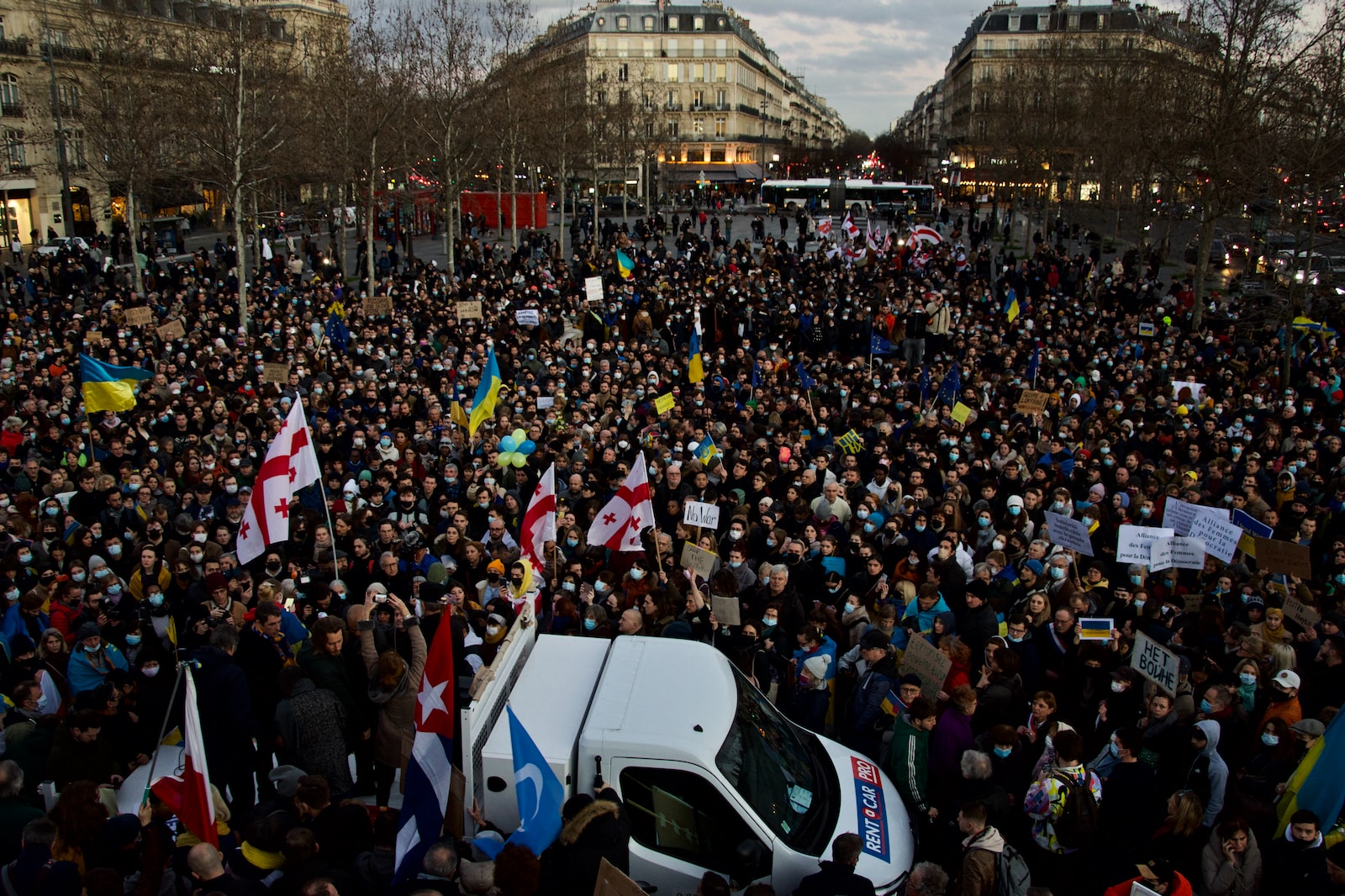 a large crowd of people standing around a white van