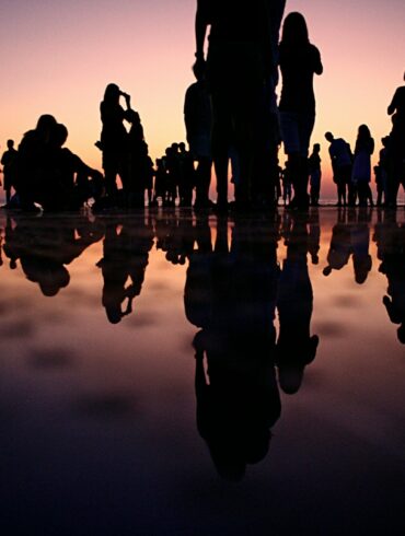 silhouette of people standing on mirror during golden hour