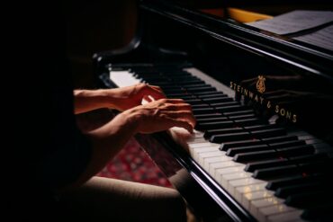 person playing black upright piano
